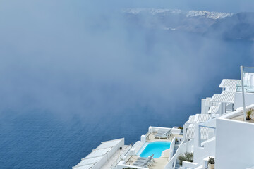 Stunning villa with swimming pool in the typical whitewashed Cycladic style overlooking a foggy Aegean Sea in Imerovigli Santorini