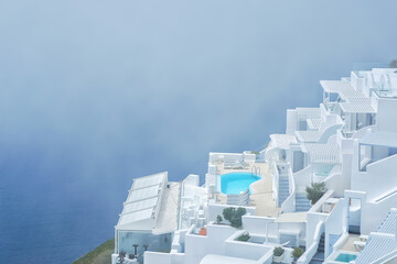 Stunning villa with swimming pool in the typical whitewashed Cycladic style overlooking a foggy Aegean Sea in Imerovigli Santorini - obrazy, fototapety, plakaty
