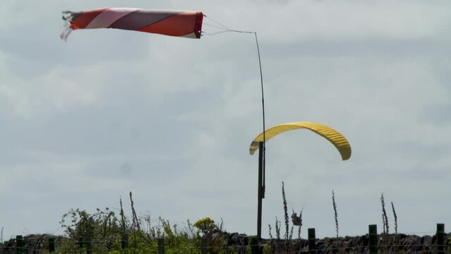 Windsock in breeze yellow paraglider summer heat haze floats in the background