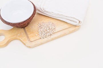 grani di orzo perlato da agricoltura biodinamica su tagliere in legno con ciotola e canovaccio bianco