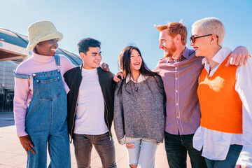 hug in group of multicultural friends.Five young people enjoying a sunny day. Teenagers laughing and talking with positive attitude.