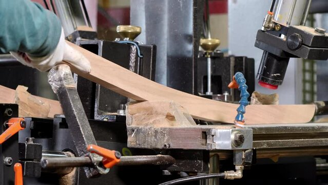 Furniture factory. A worker processes wood products on a special machine. Close-up of the product at an angle of 45 degrees