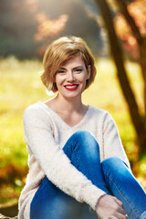 Obraz premium Portrait of pretty cheerful woman posing in park on sunny autumn day