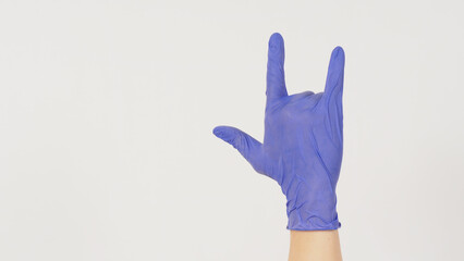 The i love you hand sign.Hand wear purple latex gloves on white background.