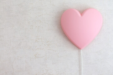 A pink lamp in the shape of a heart on a light wall in the room. Selective focus with copy space,...