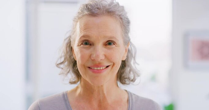 Face portrait of mature woman smiling and standing alone at home. Closeup headshot of happy senior feeling content, confident, proud and enjoying. Showing white teeth after whitening dental treatment