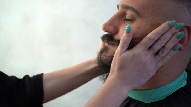 Female barber uses oil massage to grow and strengthen beard to man. Barbershop, hairstyling