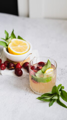 lemonade in glass on light gray concrete background. fresh summer pink drink with lemon, cherry and mint. copy space