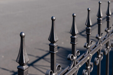 A lit metal fence with spikes. Exterior design.
