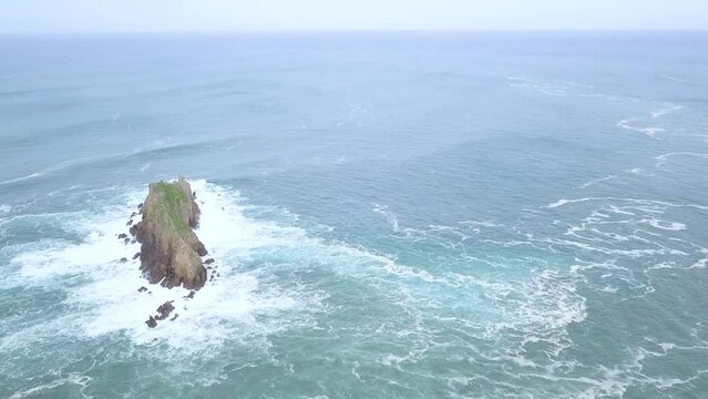 Aerial shot of Rocky Island Billano Irla with crashing waves in the ocean.