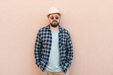 Bearded man in summer clothes and hat stand over beige wall on street city urban and travel concept - copy space and empty space for advertising