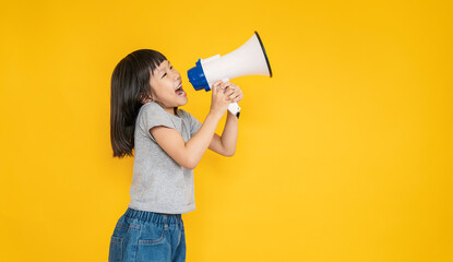 Portrait of young fun smart happy little asian girl isolated on yellow studio shot. Education for...