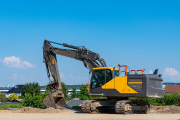 Large black and yellow excavator without a driver at a construction site.