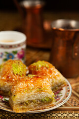 Still life with hot oriental coffee brewed in cezve. On the Arabic table is a small coffee cup and delicious honey baklava with pistachios on a saucer. Side view