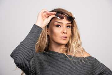 Charming woman in eyeglasses standing on gray background