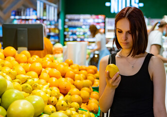 Young woman choosing lemon while shopping in supermarket.