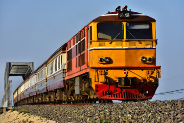 Passenger train by diesel locomotive on the railway in Thailand.