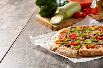 Vegetarian pizza with zucchini, tomato, peppers and mushrooms on wooden table. Copy space