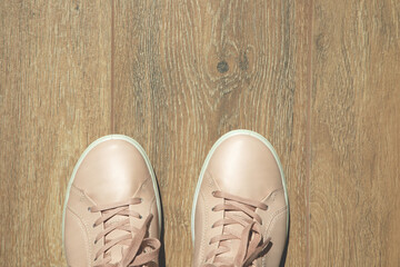 Light pink sneakers close-up on a wooden background. View from above