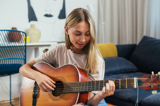 teenager girl playing acoustic guitar at home