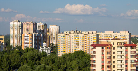 Panoramic top view - cityscape with modern buildings and lush tree foliage on a clear sunny summer day and blue sky