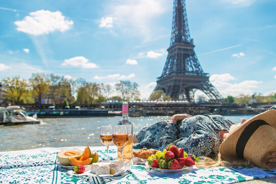 A woman near the Eiffel Tower drinks wine. Selective focus.