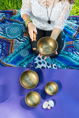 Top view of a woman holding and playing a Tibetan singing bowl.