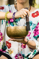 Detail of a woman's hands holding and playing a Tibetan singing bowl