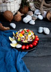 Fish salad with sardines, harringe, tuna, tomato, lemon, lettuce, cabbage, olives, beans, corn, carrotes and eggs on rustic kitchen table