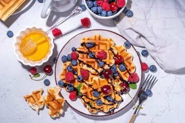 Sweet waffles with berry. Homemade summer breakfast belgian waffles with raspberries, blueberries, strawberry honey and chocolate dip sauce, copy space