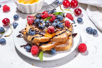 Summer breakfast with french toast. Baked with toasts with berries (blueberries, strawberries) and honey, traditional morning sweet dessert with fresh ripe berry