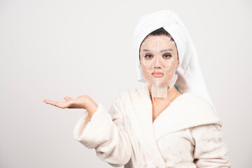 Woman wearing bathrobe and towel with facemask