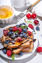 Summer breakfast with french toast. Baked with toasts with berries (blueberries, strawberries) and honey, traditional morning sweet dessert with fresh ripe berry