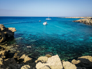 View of the sea and cliffs of Blue Lagoon, Cape Greco, Cyprus. Small boats anchored at the bay. 
