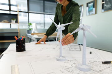 Asian young businesswoman with windmill models at table in office
