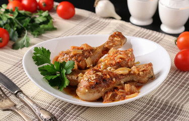 Baked chicken drumsticks with vegetables, spices and parsley on white plate