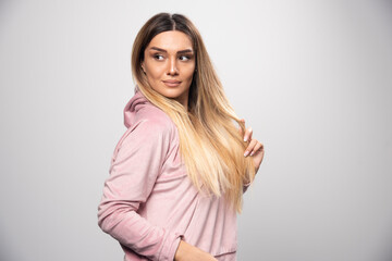 Blond lady in pink sweatshirt posing in elegant and seductive manner