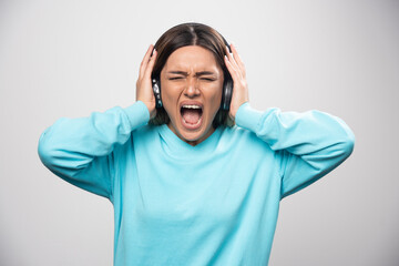 Blonde girl in blue sweatshirt listens the headphones and does not enjoy the music