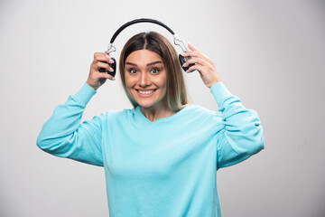 Blonde girl in blue sweatshirt holding headphones and gets ready to wear them to listen to the music