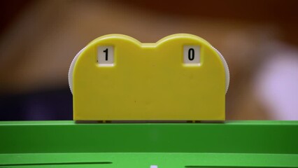 Close-up of a players hand updating the score on a plastic board game scoreboard. Gameplay, competition, user engagement. Leisure activity, tabletop games, board games, family games.