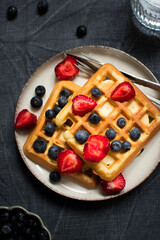 Traditional belgian waffles with fresh berries on dark background