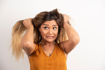 Young woman touching her hair and posing on white background