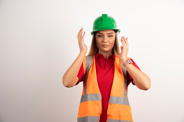 Proud female worker posing with green helmet on white background