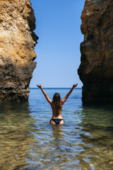 Anonymous woman in sea near rocks