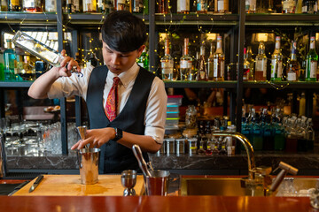 Professional male bartender preparing and serving cocktail drink to customer on bar counter at luxury nightclub. Barman making mixed alcoholic drink for celebrating holiday party at restaurant bar.