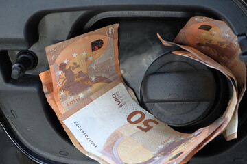 Euro money in car fuel tank opening.