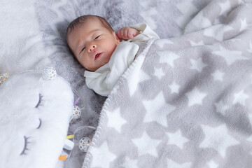 newborn girl woke up, lies covered with a blanket