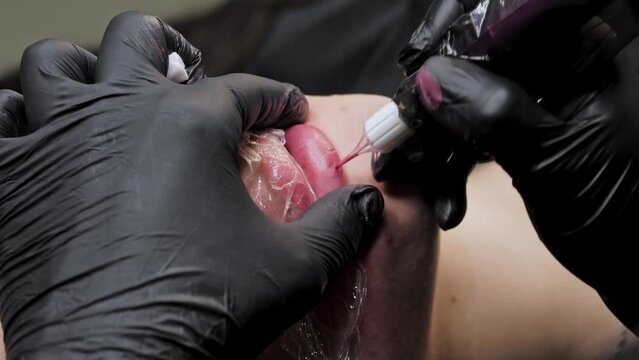 Close-up of a permanent makeup procedure. A needle pierces the lips and injects paint under the skin. Macro