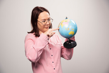 Fototapeta premium Portrait of woman looking on an Earth globe on a white background