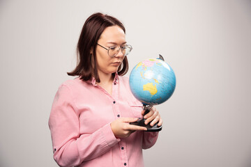 Fototapeta premium Portrait of woman looking on an Earth globe on a white background